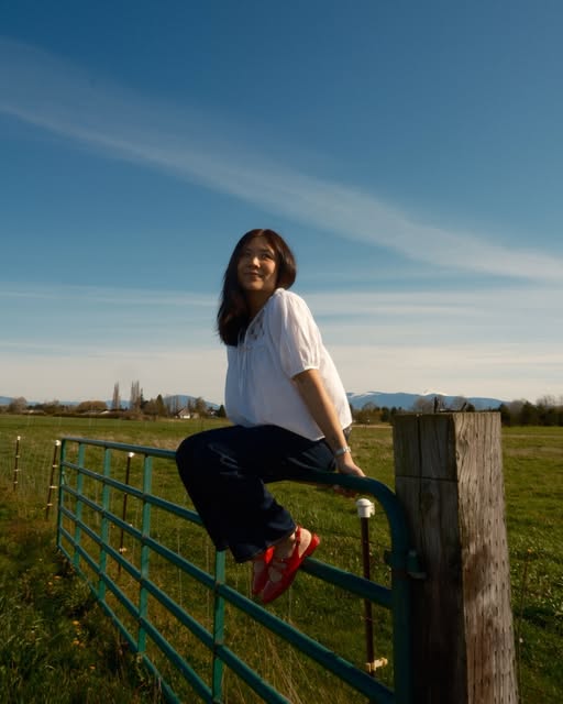 A relaxed portrait on a farm gate beneath a blue sky