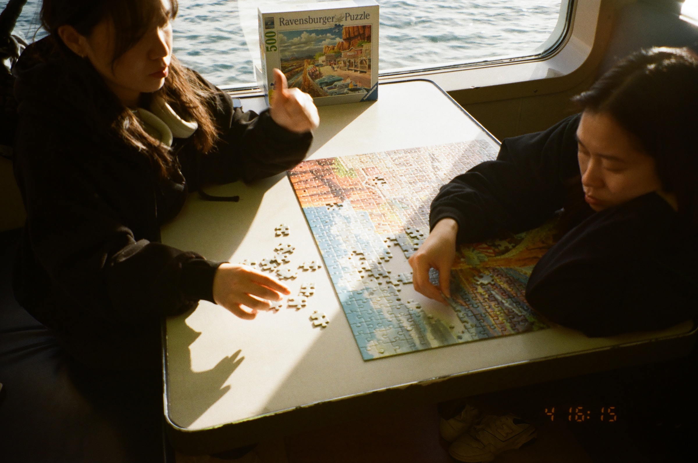 Hands working on a puzzle in warm light aboard a ferry
